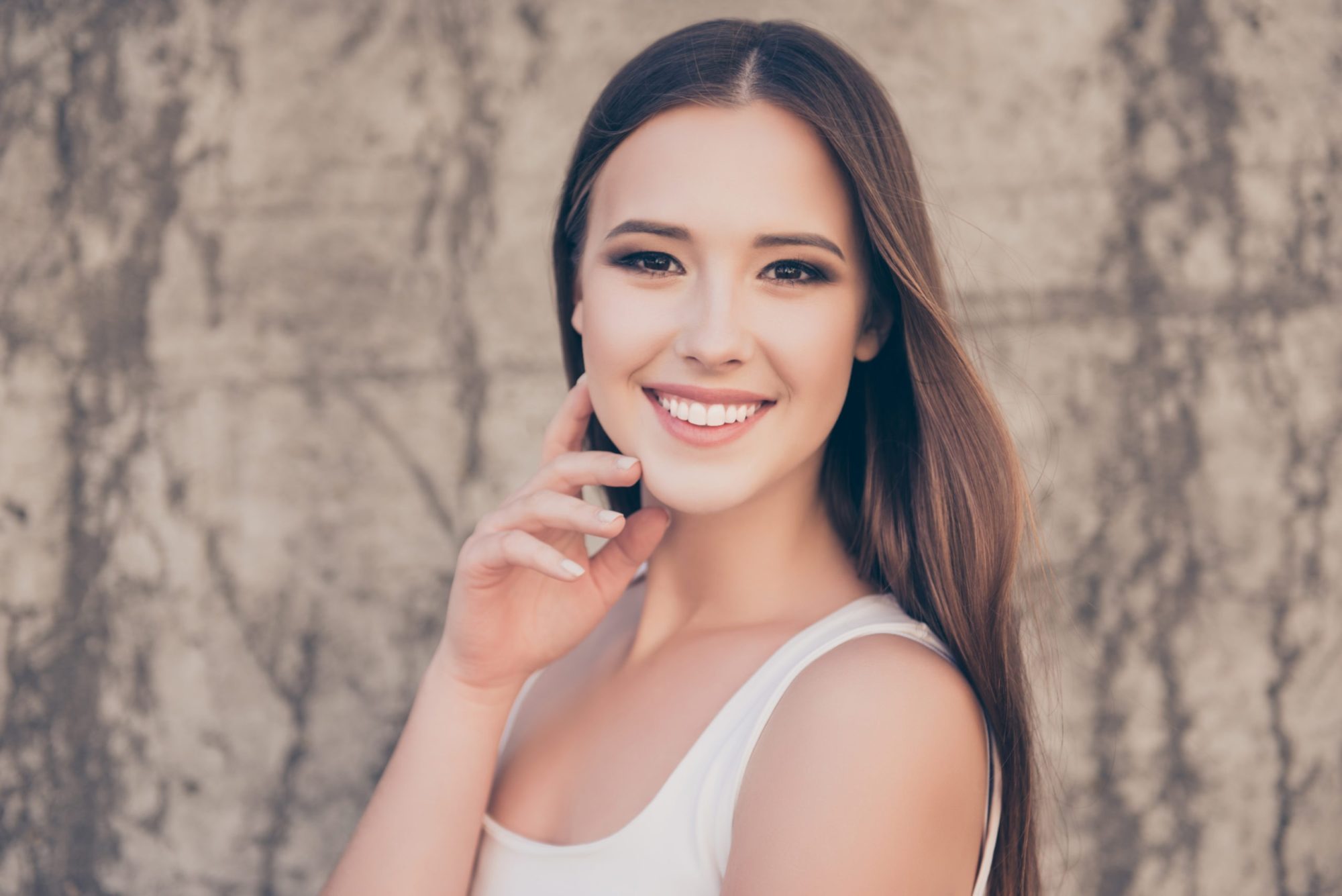 Close up cropped portrait of a gorgeous and healthy young lady, smiling on the concrete backgroung outdoors, with beaming smile and smooth skin braces grand rapids